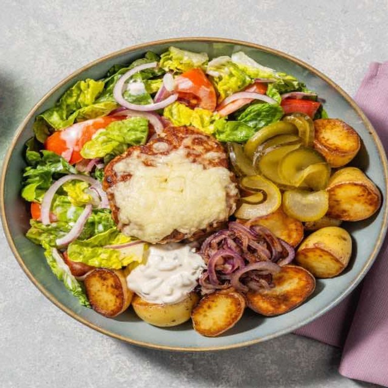 Duitse biefstuk met frisse salade met gebakken krieltjes, augurk en gesmolten cheddar