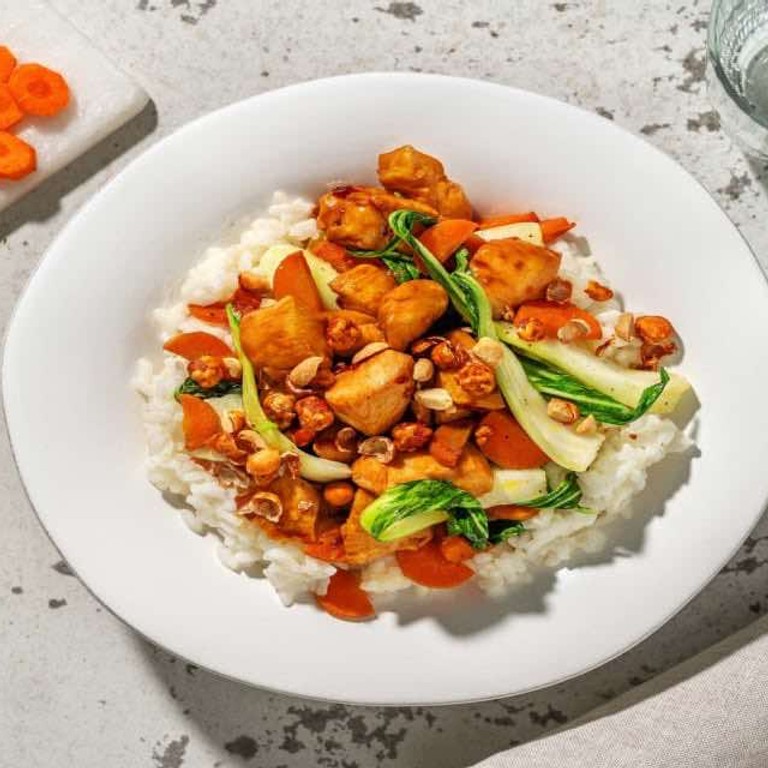 Kipfilethaasjes in zoete saus met knoflookrijst met paksoi en topping van pikante honingpinda's