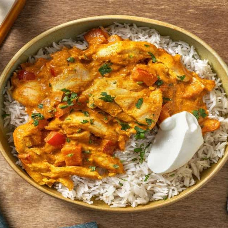 Kruidige curry met kippendij met rijst, verse koriander en yoghurt