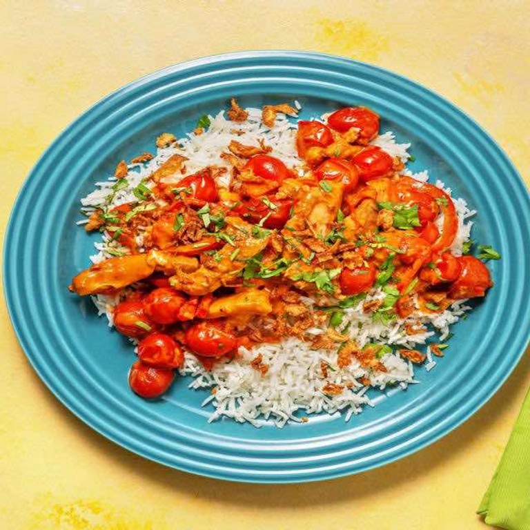 Pittige curry met kip en rijst met paprika, cherrytomaten en verse koriander