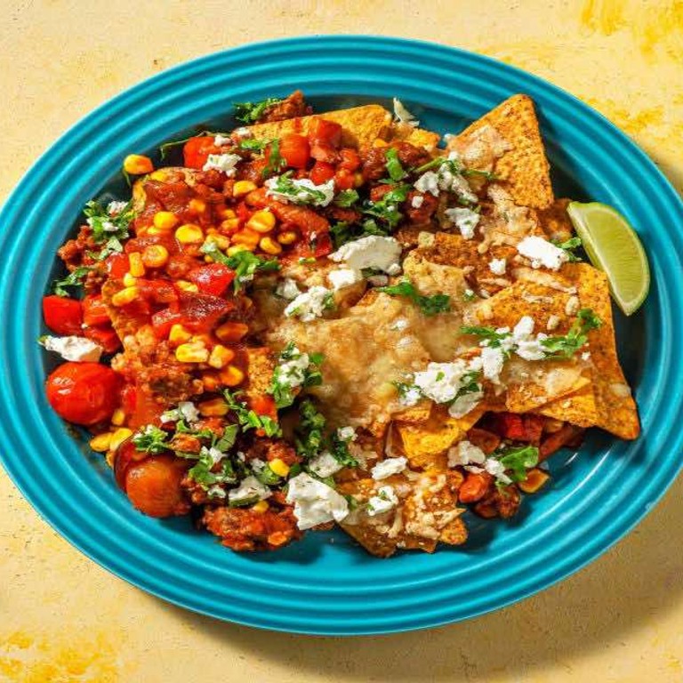 Pittige nachoschotel met gehakt en cheddar met verse koriander en witte-kaassalsa