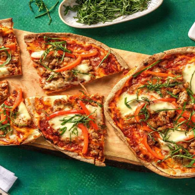 Platbroodpizza's met gekruid varkensgehakt en mozzarella met paprika, tomatensaus en basilicum