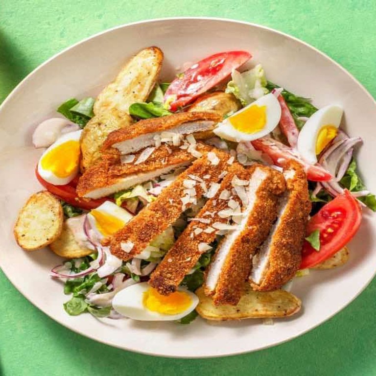 Salade met schnitzelreepjes en gebakken krieltjes met romaine sla, een gekookte eitje en provolone