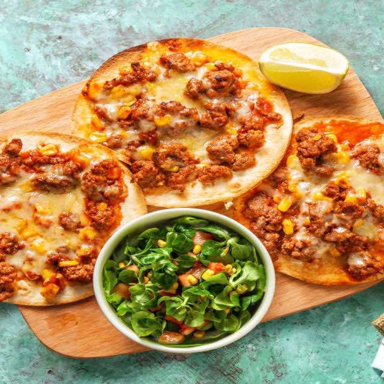 Tostada met gekruid kipgehakt en cheddar met frisse salade van mais en tomaat